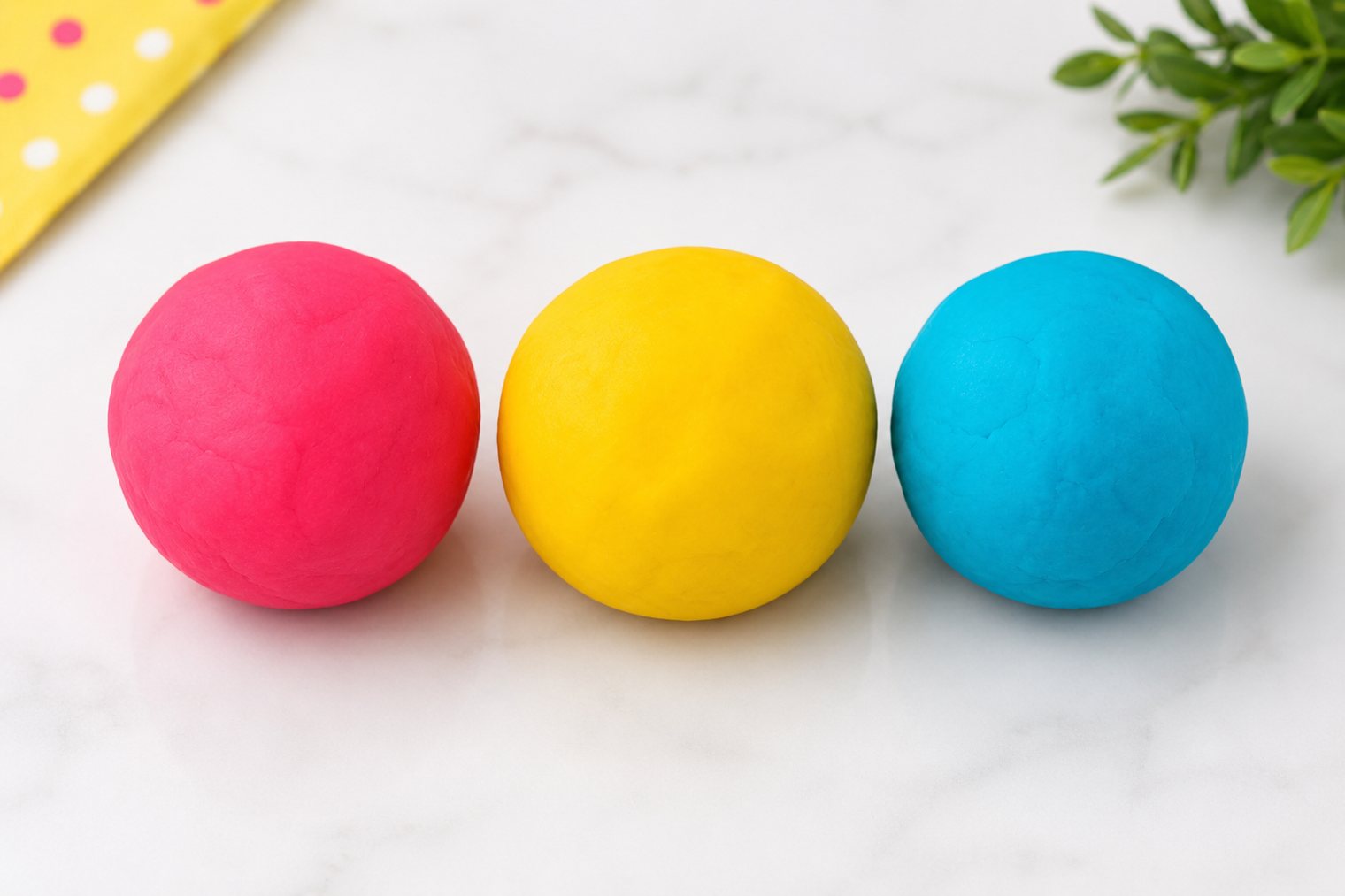 Three balls of scented play dough in pink, yellow and blue.