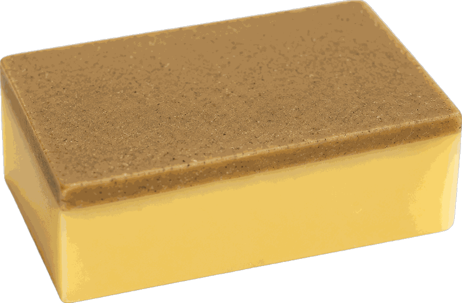 A goat's milk soap bar turned to show the ground pumice scrub layer.